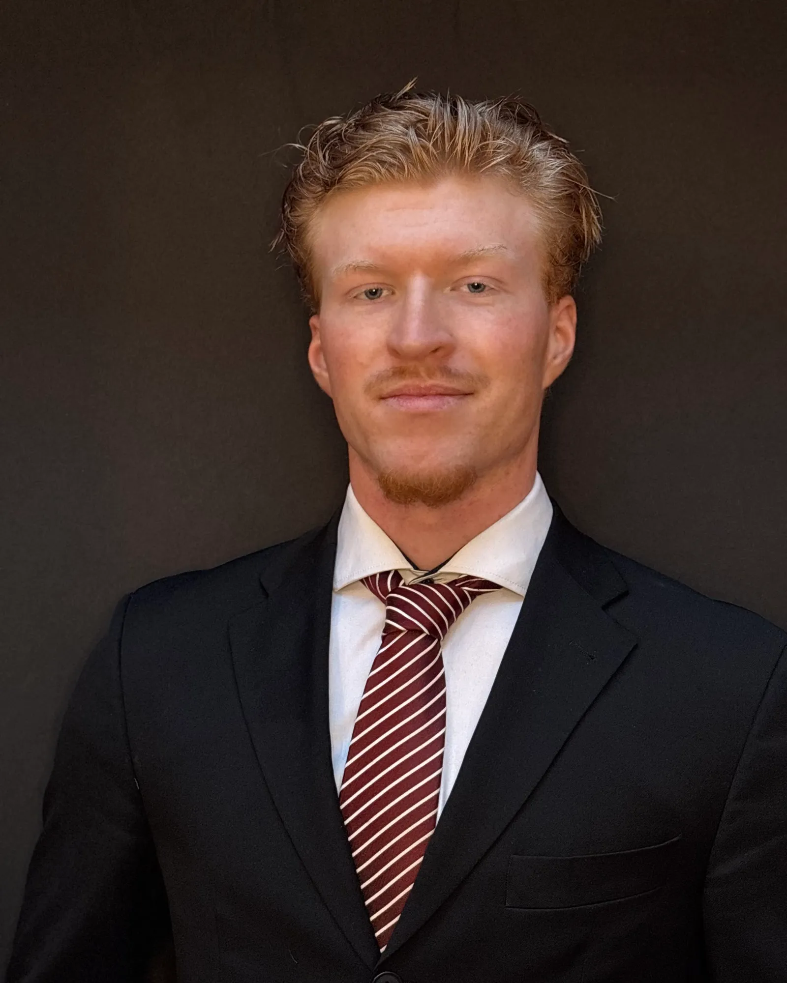 Porträt von Magnus Buchner im dunklen Anzug vor dunklem Hintergrund